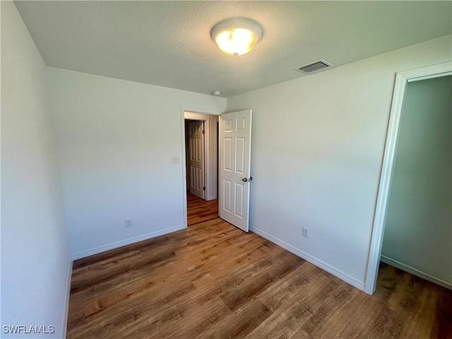 unfurnished bedroom with wood-type flooring, a textured ceiling, and a closet