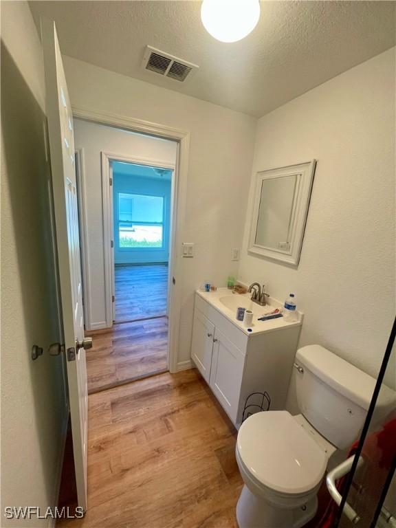 bathroom featuring a textured ceiling, vanity, hardwood / wood-style flooring, and toilet