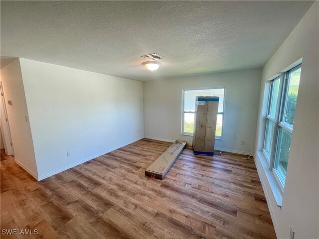 spare room with a textured ceiling and light hardwood / wood-style flooring