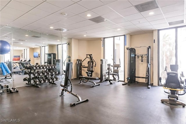 gym featuring a wall of windows and a drop ceiling