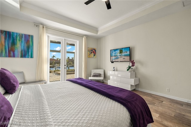 bedroom with ornamental molding, access to exterior, a raised ceiling, and wood finished floors