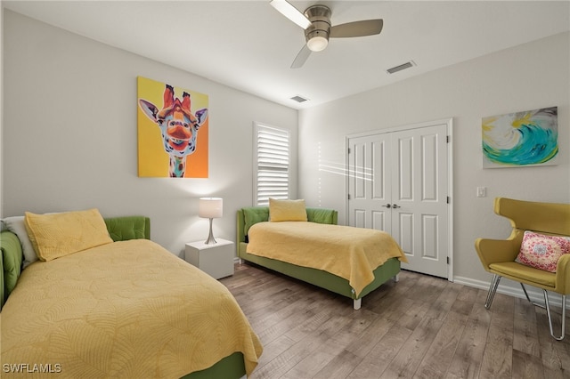 bedroom featuring wood finished floors, visible vents, a ceiling fan, and a closet