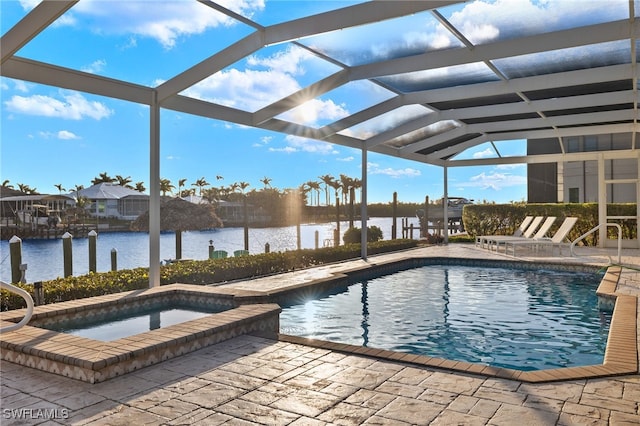 view of pool with an in ground hot tub, a patio, a water view, and glass enclosure