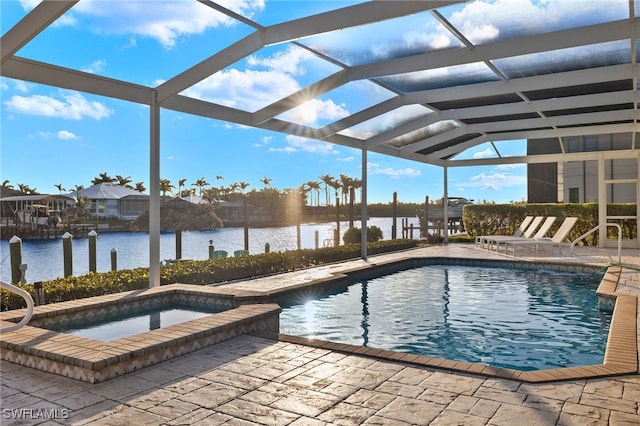 pool featuring glass enclosure, a water view, an in ground hot tub, and a patio area