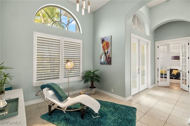 sitting room featuring light tile patterned floors, a towering ceiling, and french doors