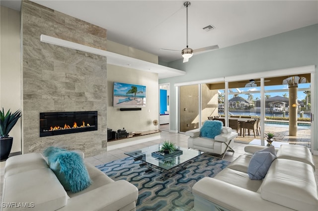 living room with ceiling fan, light tile patterned flooring, and a tiled fireplace