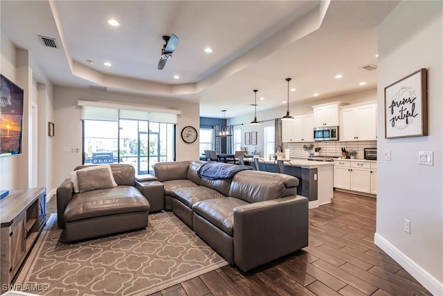 living room featuring dark hardwood / wood-style floors, a wealth of natural light, and a tray ceiling