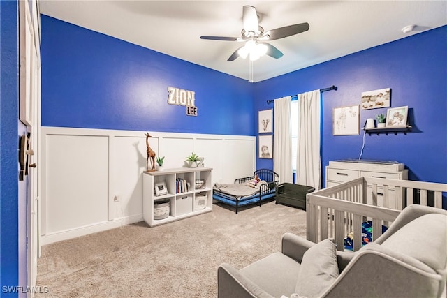 bedroom with a crib, light carpet, and ceiling fan