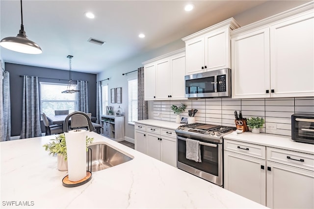 kitchen with pendant lighting, sink, white cabinetry, and stainless steel appliances