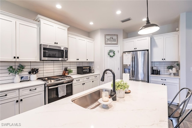 kitchen with pendant lighting, sink, stainless steel appliances, and tasteful backsplash