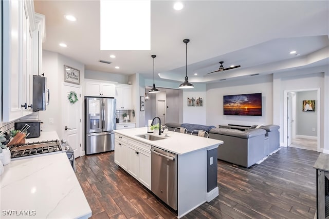 kitchen with an island with sink, sink, white cabinets, and stainless steel appliances