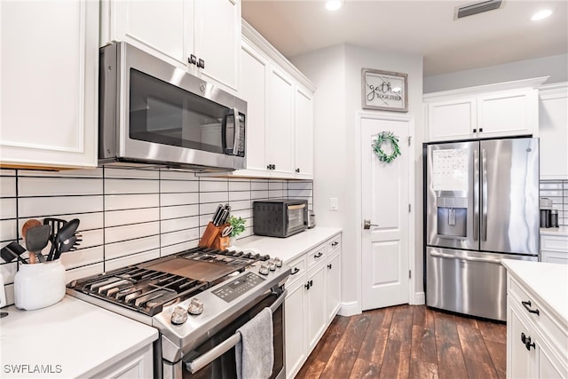 kitchen featuring white cabinets, appliances with stainless steel finishes, dark hardwood / wood-style flooring, and tasteful backsplash