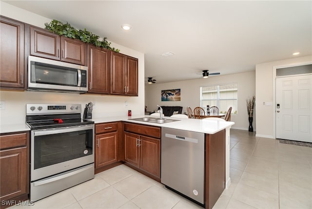 kitchen featuring ceiling fan, sink, kitchen peninsula, light tile patterned floors, and appliances with stainless steel finishes