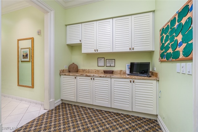 kitchen featuring white cabinetry, crown molding, light tile patterned floors, and light stone counters