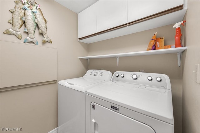 clothes washing area featuring cabinet space and washing machine and clothes dryer