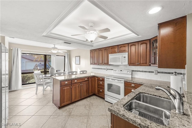 kitchen with a tray ceiling, visible vents, a sink, white appliances, and a peninsula