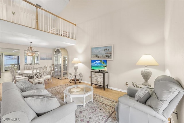 living room featuring light wood-style floors, a high ceiling, and baseboards