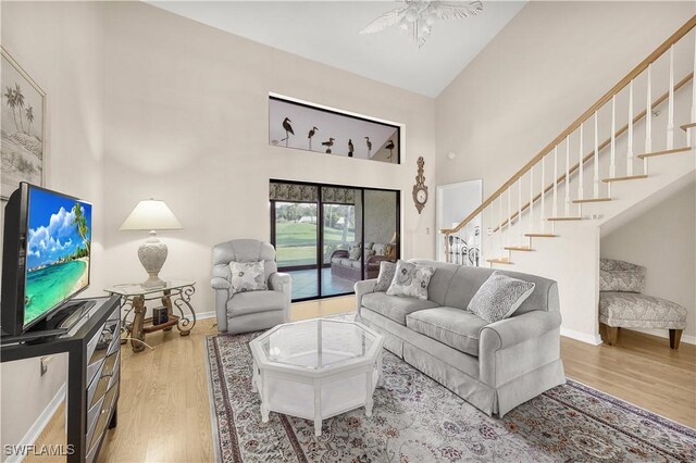 living room with ceiling fan, high vaulted ceiling, and light hardwood / wood-style flooring