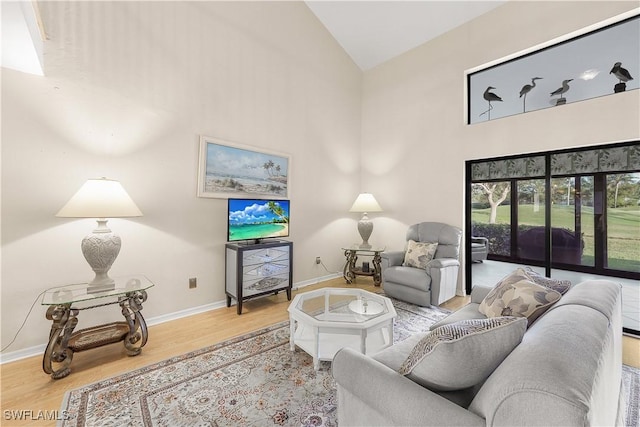 living room with high vaulted ceiling, wood finished floors, and baseboards