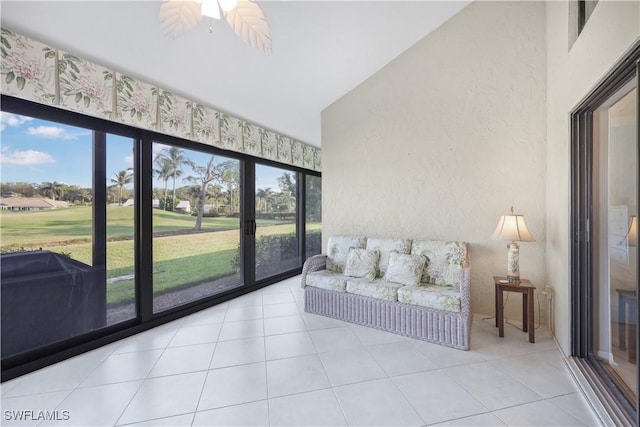 interior space with ceiling fan, high vaulted ceiling, tile patterned flooring, and a textured wall