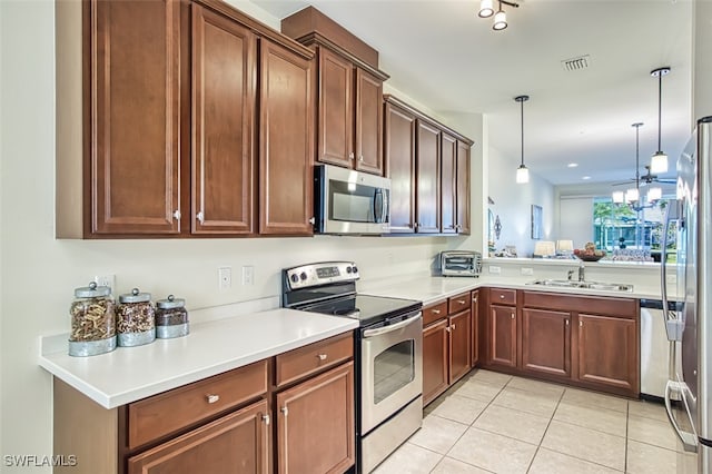 kitchen with pendant lighting, sink, light tile patterned floors, appliances with stainless steel finishes, and kitchen peninsula