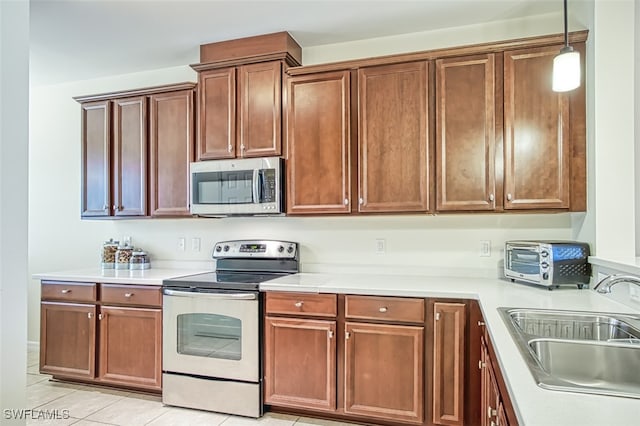 kitchen with appliances with stainless steel finishes, light tile patterned floors, hanging light fixtures, and sink