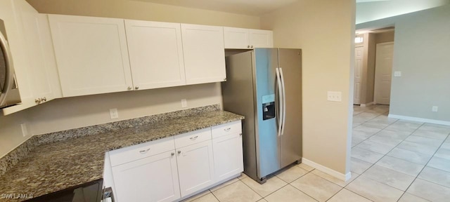 kitchen with white cabinetry, dark stone countertops, stainless steel fridge with ice dispenser, and light tile patterned floors