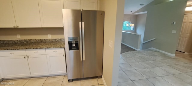 kitchen featuring hanging light fixtures, stainless steel refrigerator with ice dispenser, dark stone counters, lofted ceiling, and white cabinets