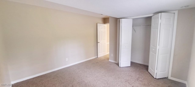 unfurnished bedroom featuring light carpet and a closet