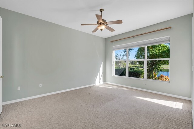 empty room featuring carpet, ceiling fan, and a water view