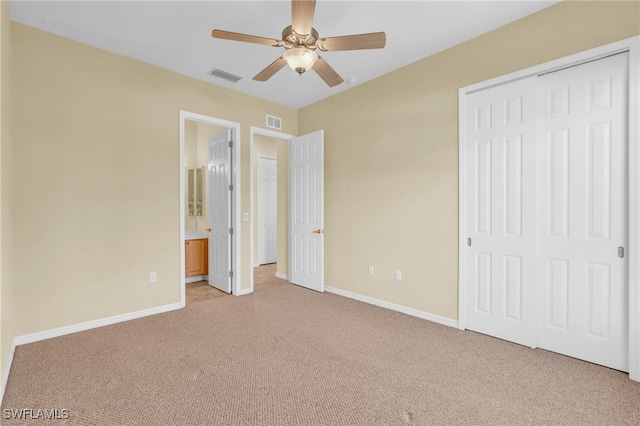 unfurnished bedroom featuring ceiling fan, light colored carpet, connected bathroom, and a closet