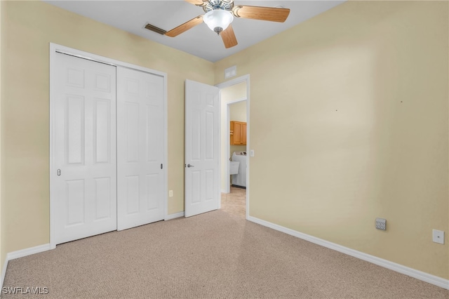 unfurnished bedroom featuring washer / dryer, light colored carpet, a closet, and ceiling fan