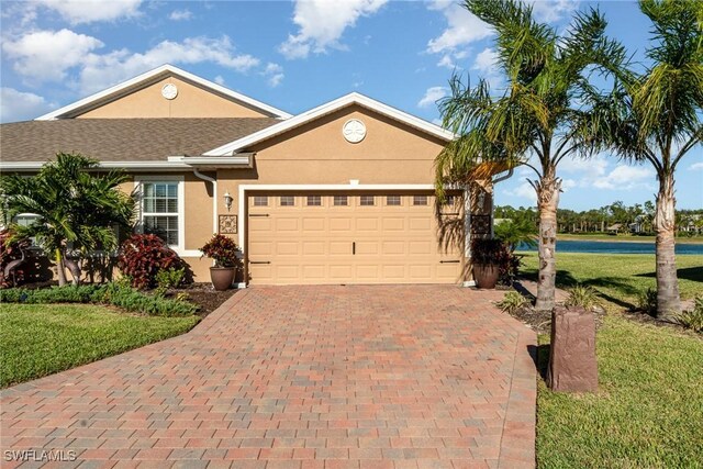 single story home with an attached garage, a front lawn, decorative driveway, and stucco siding