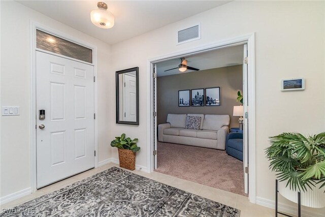 foyer featuring light carpet, light tile patterned floors, visible vents, baseboards, and ceiling fan