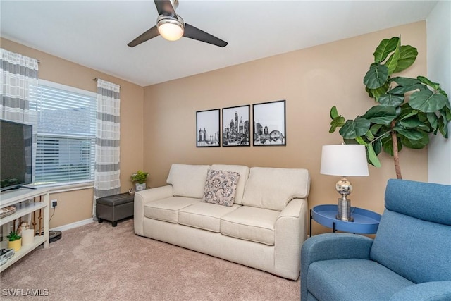 living area featuring baseboards, a ceiling fan, and carpet flooring