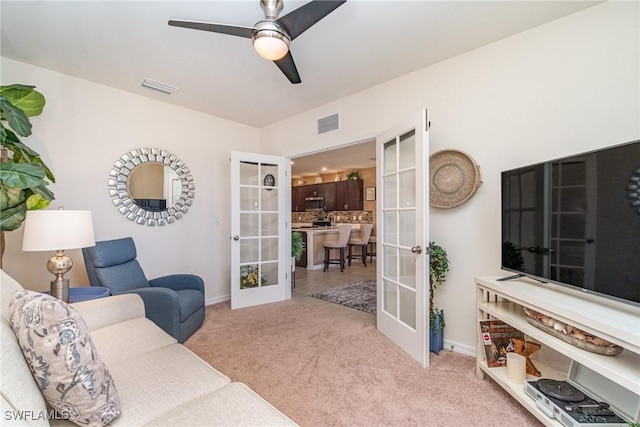 living area with carpet floors, french doors, visible vents, and a ceiling fan