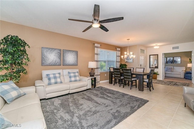 living area with ceiling fan with notable chandelier, visible vents, baseboards, and light tile patterned flooring