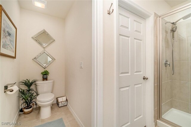 full bathroom featuring baseboards, a stall shower, toilet, and tile patterned floors