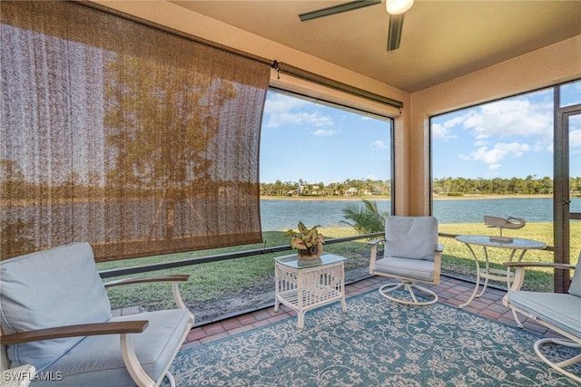 sunroom with ceiling fan and a water view