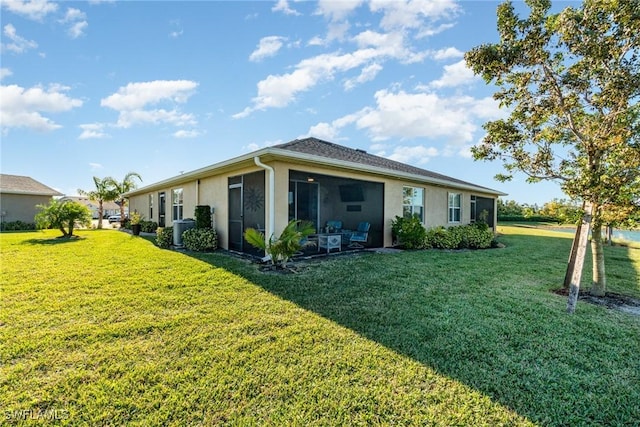 rear view of house featuring a yard, central AC unit, and stucco siding