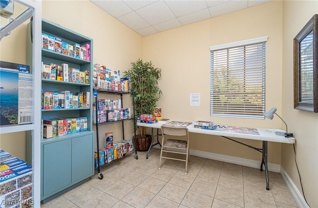 office area featuring a paneled ceiling, tile patterned flooring, and baseboards