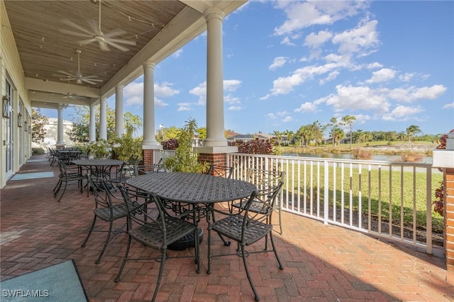 view of patio / terrace featuring a ceiling fan, outdoor dining space, and a water view