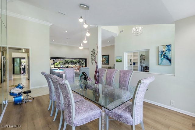 dining area featuring light hardwood / wood-style flooring, an inviting chandelier, a high ceiling, and ornamental molding