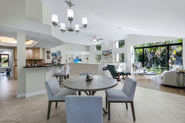 tiled dining room with ceiling fan with notable chandelier