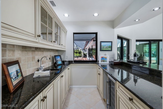 kitchen featuring sink, dark stone counters, and cream cabinetry