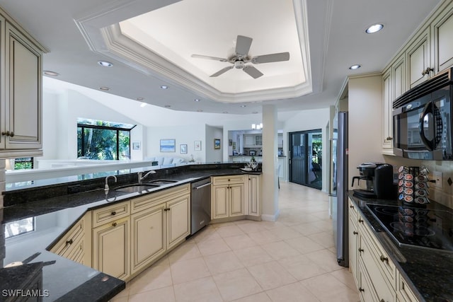 kitchen with dark stone counters, a raised ceiling, black appliances, and cream cabinetry