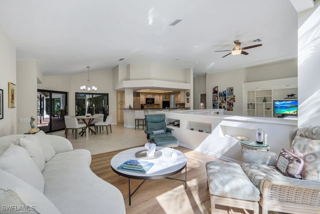 living room featuring ceiling fan with notable chandelier, lofted ceiling, and light hardwood / wood-style flooring