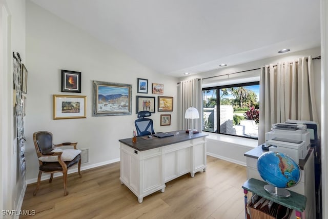 home office with light hardwood / wood-style floors and lofted ceiling