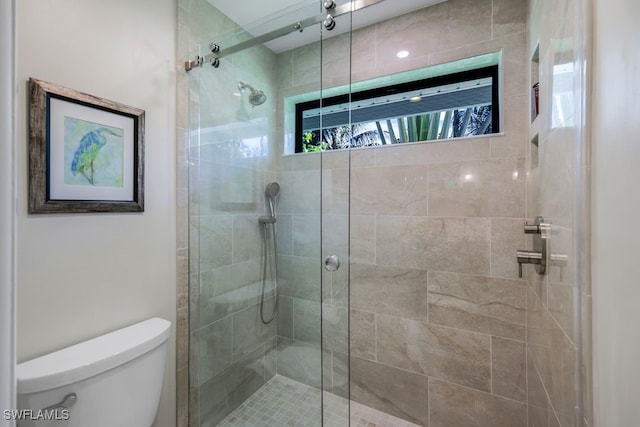 bathroom with toilet and a shower with shower door