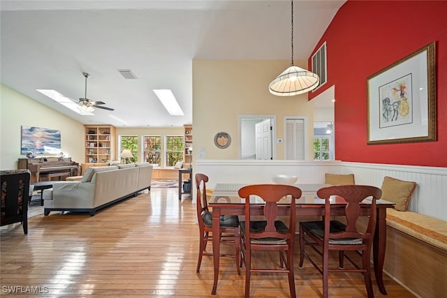 dining area with a skylight, ceiling fan, high vaulted ceiling, and hardwood / wood-style flooring